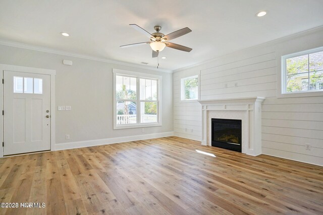 unfurnished living room featuring crown molding, a ceiling fan, a glass covered fireplace, and light wood-style flooring