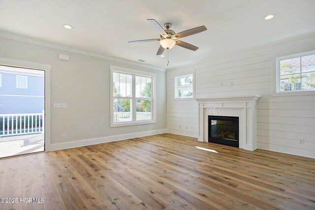 unfurnished living room with a glass covered fireplace, hardwood / wood-style floors, a ceiling fan, baseboards, and ornamental molding