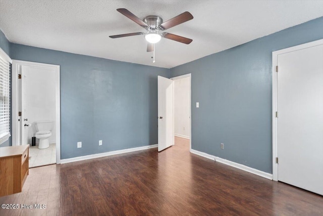 unfurnished bedroom with baseboards, connected bathroom, ceiling fan, and wood finished floors