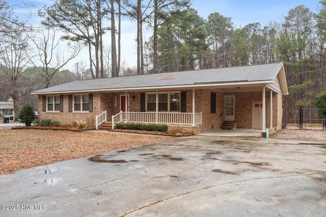 single story home with covered porch, a carport, driveway, and brick siding
