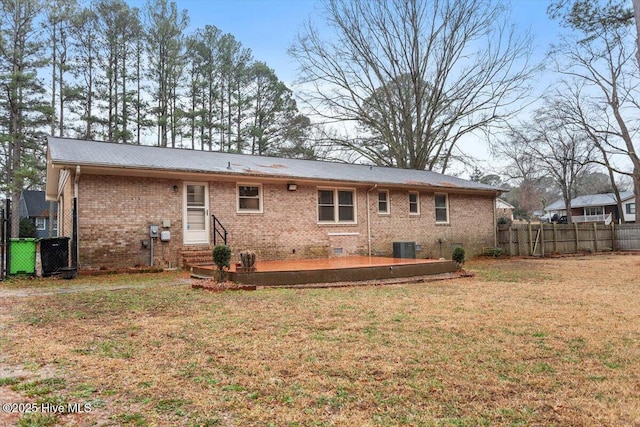 rear view of house with a lawn, brick siding, fence, and entry steps