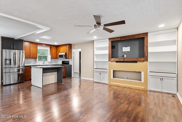 kitchen featuring stainless steel appliances, a ceiling fan, open floor plan, a kitchen island, and dark wood-style floors