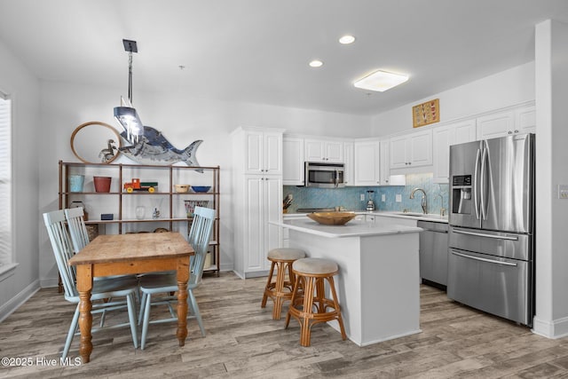 kitchen featuring appliances with stainless steel finishes, a sink, light wood-style floors, and recessed lighting