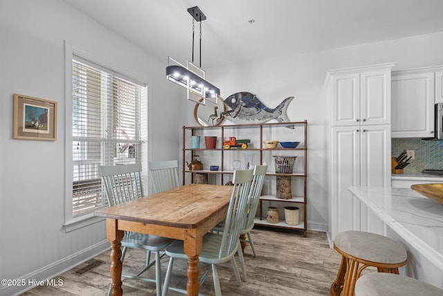 dining room featuring light wood finished floors and baseboards
