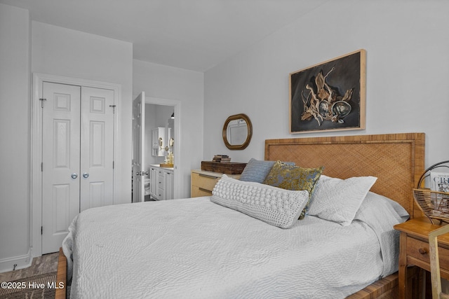 bedroom featuring a closet, wood finished floors, and ensuite bath