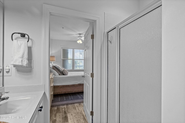 ensuite bathroom with wood finished floors, a stall shower, ceiling fan, and vanity