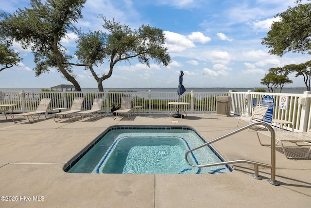 view of swimming pool featuring a patio, fence, a swimming pool, and a water view