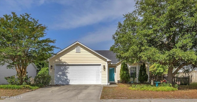 view of front of house featuring fence, driveway, and a garage