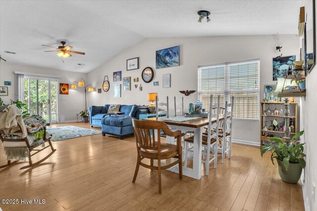 dining room featuring ceiling fan, visible vents, light wood-type flooring, baseboards, and lofted ceiling