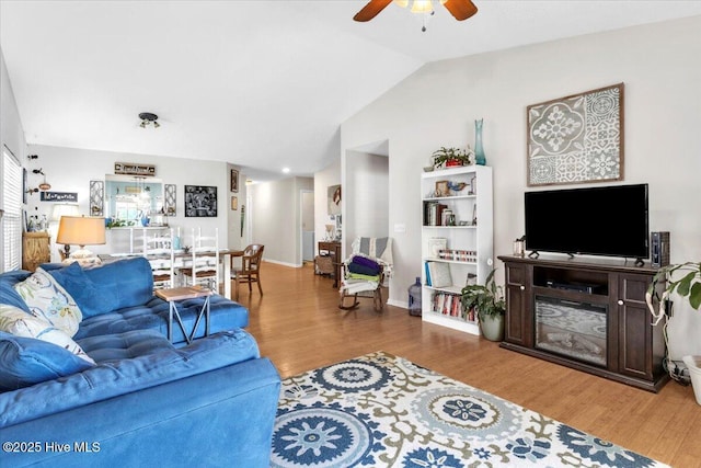 living area with baseboards, a ceiling fan, wood finished floors, and lofted ceiling