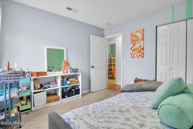 carpeted bedroom featuring a textured ceiling, visible vents, baseboards, and a closet