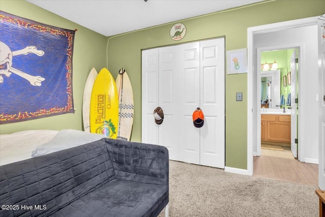 bedroom with a closet, baseboards, and light carpet