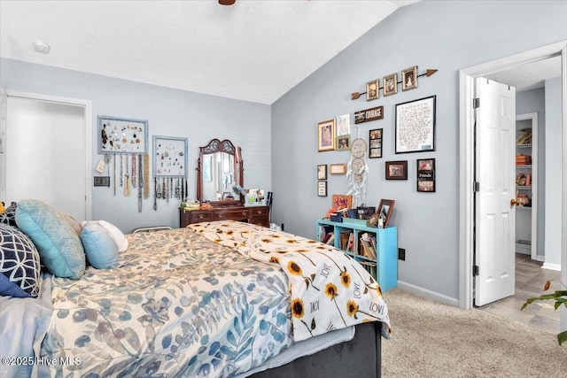 bedroom with baseboards, vaulted ceiling, and light carpet