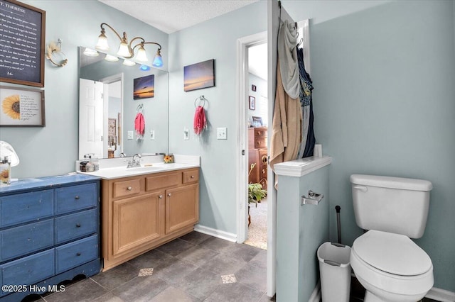 bathroom featuring toilet, baseboards, a textured ceiling, and vanity