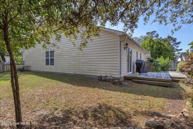 view of side of property featuring a yard, fence, and a wooden deck