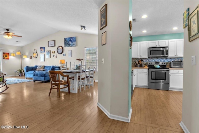 interior space with stainless steel appliances, baseboards, white cabinetry, and a textured ceiling