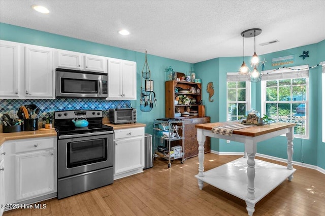 kitchen featuring light countertops, white cabinetry, appliances with stainless steel finishes, and visible vents