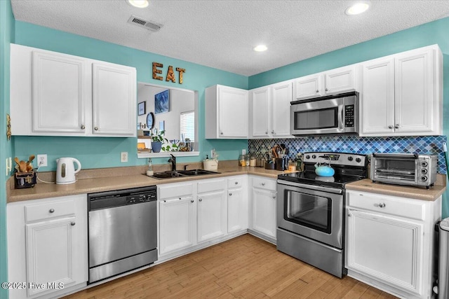 kitchen with a sink, white cabinets, and stainless steel appliances