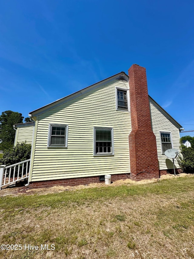 view of side of home with a lawn and a chimney
