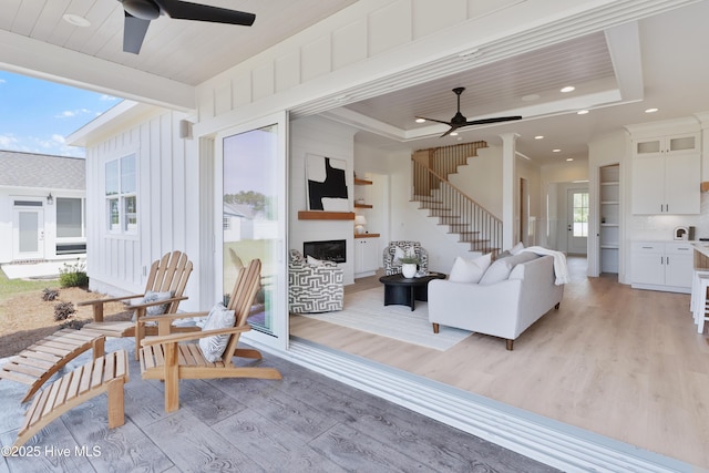 316 Lightning Bug Ln, Holly Ridge, NC 28445 - living room featuring light wood-style floors, a large fireplace, a ceiling fan, and stairs