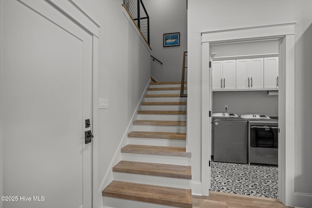 staircase featuring baseboards, wood finished floors, and washing machine and clothes dryer
