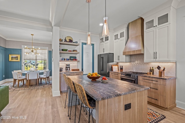 kitchen featuring custom range hood, decorative backsplash, appliances with stainless steel finishes, and light wood-type flooring