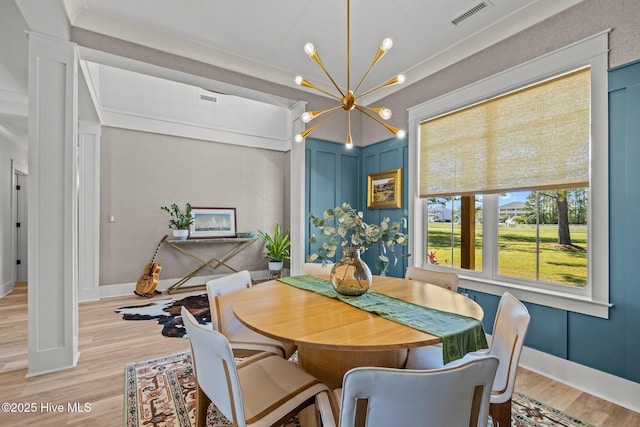 dining space with visible vents, baseboards, wood finished floors, and a chandelier