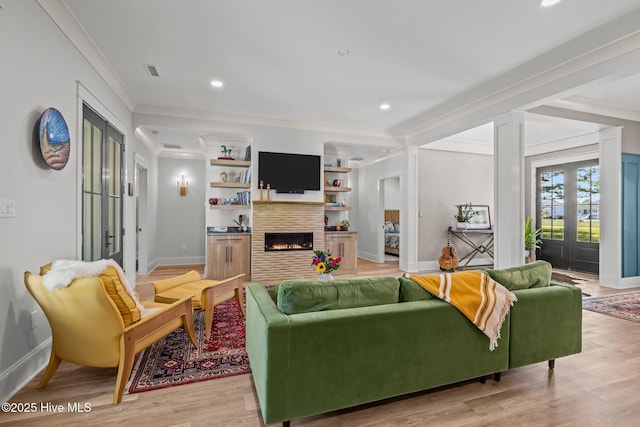 living area with crown molding, baseboards, french doors, and a warm lit fireplace