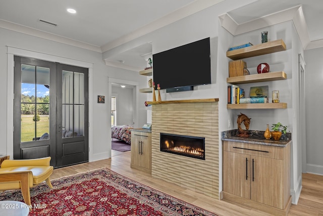 interior space with french doors, light wood finished floors, baseboards, and a tile fireplace