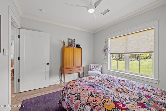 bedroom with crown molding, ceiling fan, visible vents, and wood finished floors