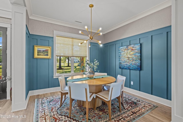 dining area featuring a decorative wall, light wood finished floors, and a chandelier