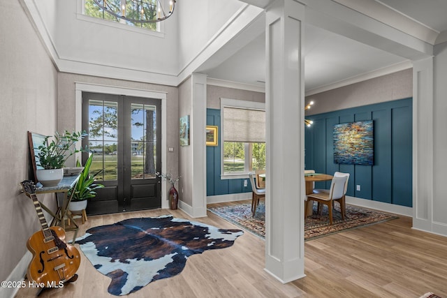 foyer featuring french doors, crown molding, plenty of natural light, and wood finished floors