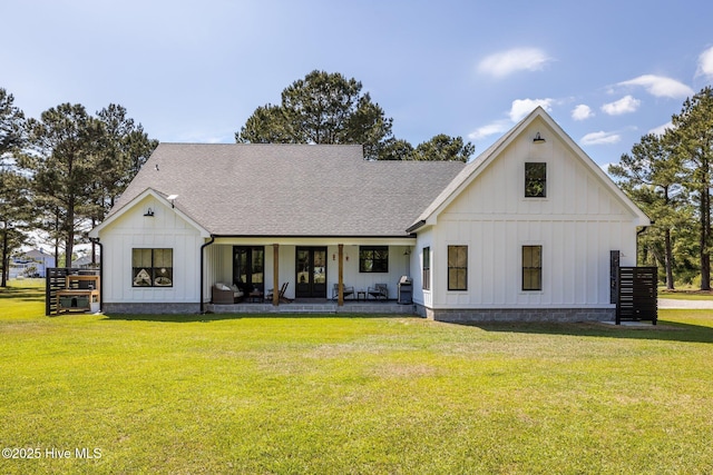 view of front of home with board and batten siding, french doors, roof with shingles, and a front lawn