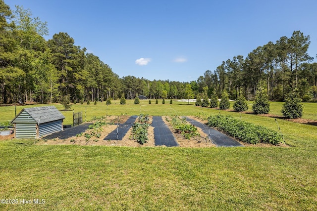 view of yard with an outdoor structure, a garden, and a wooded view