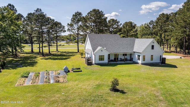 view of front facade featuring a shingled roof and a front yard