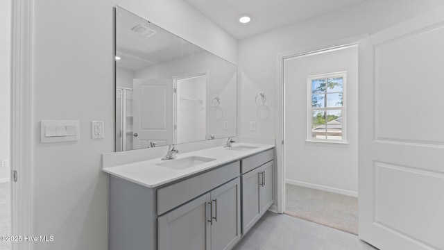 full bath featuring double vanity, baseboards, visible vents, and a sink