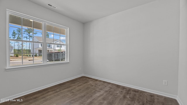 spare room with baseboards, visible vents, and dark wood finished floors