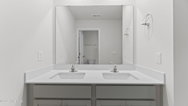 bathroom featuring double vanity, toilet, visible vents, and a sink