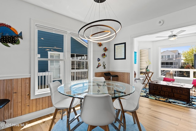 408 Dolphin St, Sunset Beach, NC 28468 - dining area with wood walls, wood finished floors, ceiling fan with notable chandelier, and a wainscoted wall
