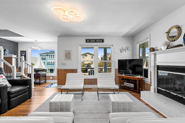 408 Dolphin St, Sunset Beach, NC 28468 - living room with a glass covered fireplace, a wainscoted wall, wood finished floors, and a wealth of natural light