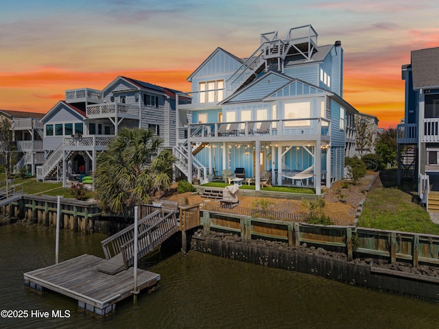 408 Dolphin St, Sunset Beach, NC 28468 - rear view of property featuring stairs, board and batten siding, a deck with water view, and a chimney
