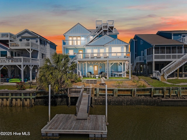 408 Dolphin St, Sunset Beach, NC 28468 - back of property featuring board and batten siding, a sunroom, a balcony, a water view, and stairs