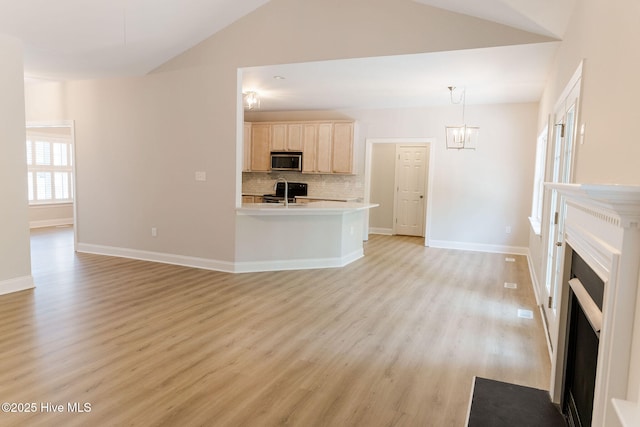 135 Live Oak Dr, Leland, NC 28451 - unfurnished living room featuring light wood finished floors, an inviting chandelier, a sink, a fireplace with flush hearth, and vaulted ceiling