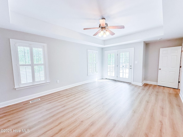 135 Live Oak Dr, Leland, NC 28451 - unfurnished living room featuring a tray ceiling, visible vents, and a healthy amount of sunlight