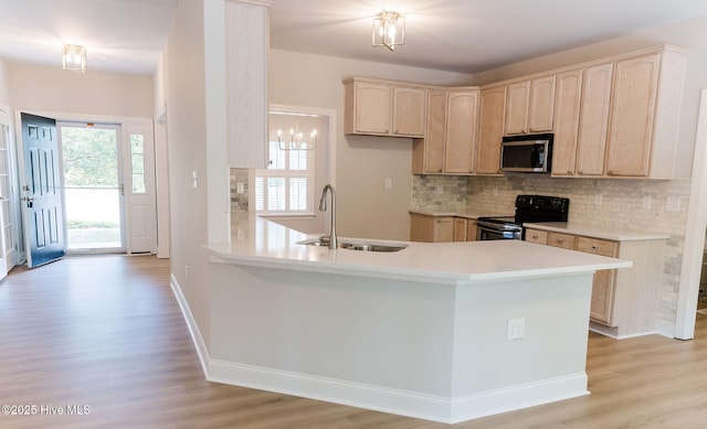 135 Live Oak Dr, Leland, NC 28451 - kitchen with a peninsula, a sink, electric range, stainless steel microwave, and light wood-style floors