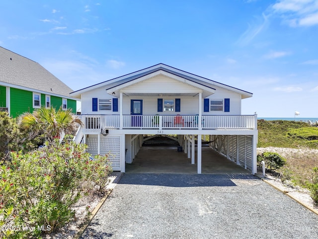 beach home featuring a carport, driveway, covered porch, and stairway