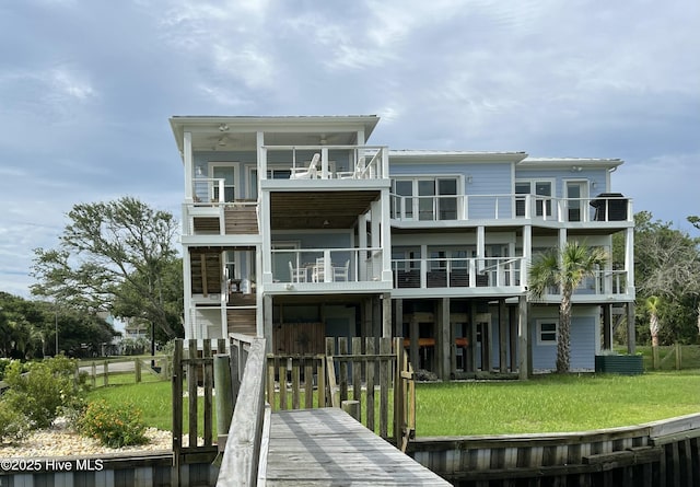back of property with fence, a yard, and a balcony