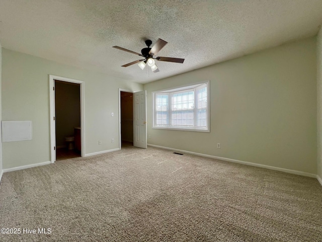 unfurnished bedroom featuring light carpet, a textured ceiling, baseboards, connected bathroom, and ceiling fan
