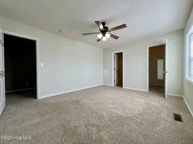 unfurnished bedroom featuring a spacious closet, carpet flooring, a textured ceiling, a closet, and baseboards