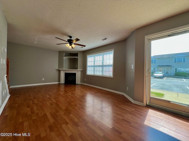 unfurnished living room with a ceiling fan, wood finished floors, a textured ceiling, a fireplace, and baseboards